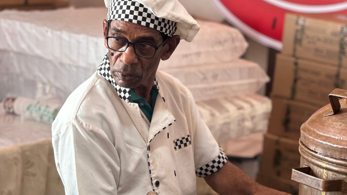 Senior cook in traditional attire preparing an Indian dish