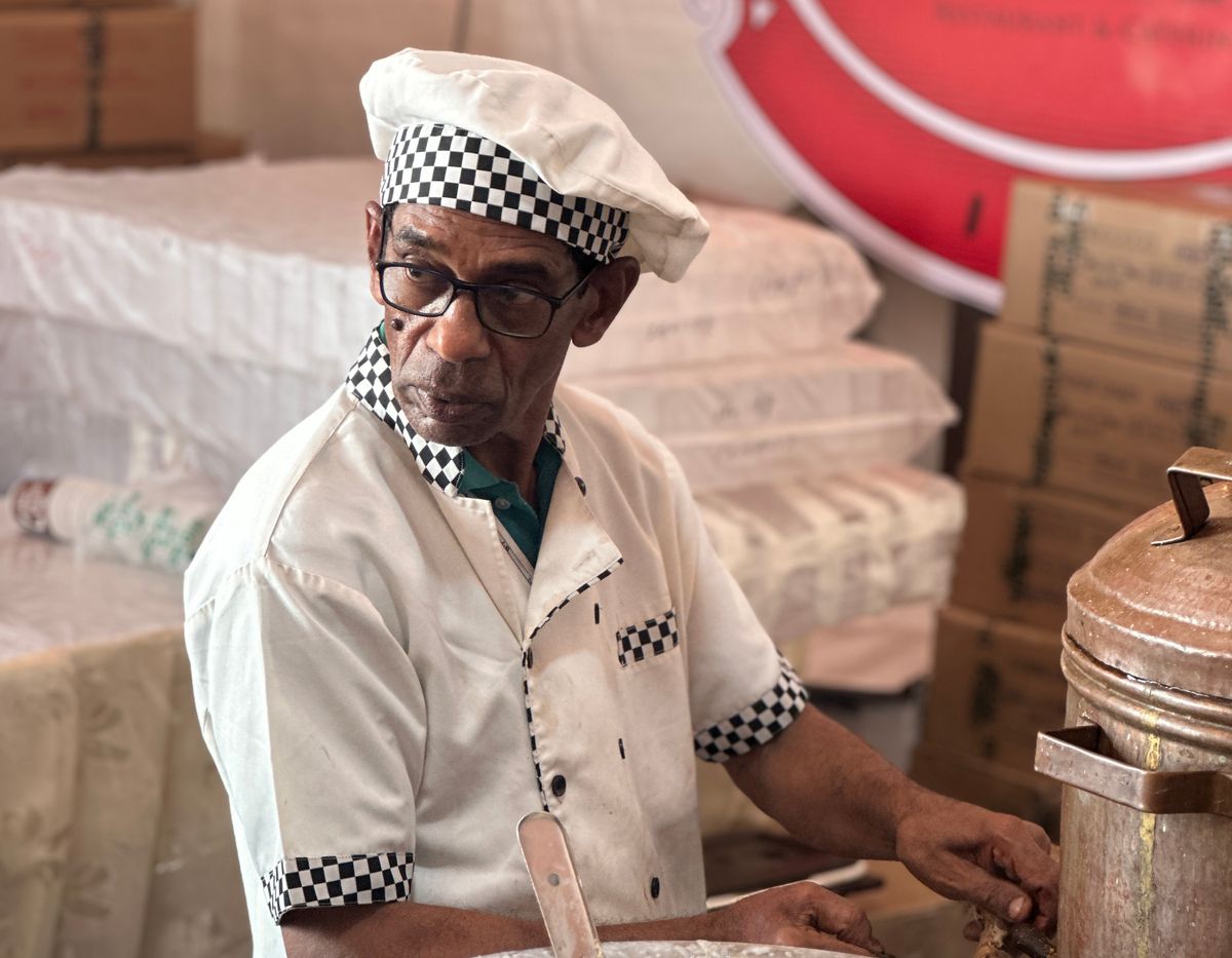 Senior cook in traditional attire preparing an Indian dish