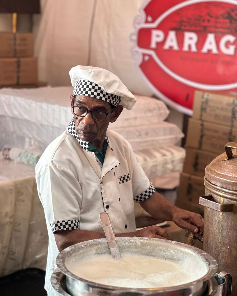 Senior cook in traditional attire preparing an Indian dish