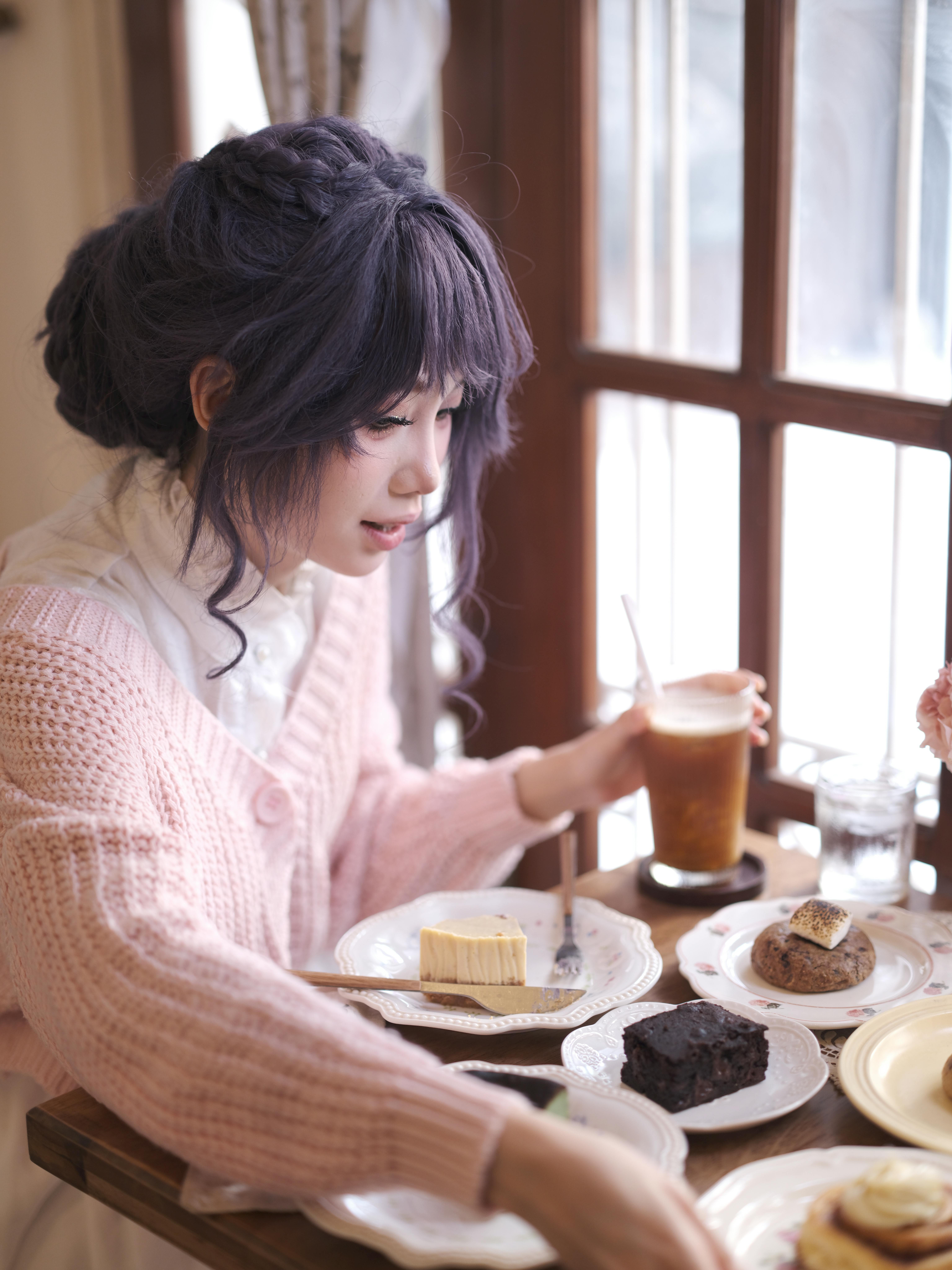 A woman enjoying coffee and dessert at a cozy cafe, capturing a serene afternoon moment.