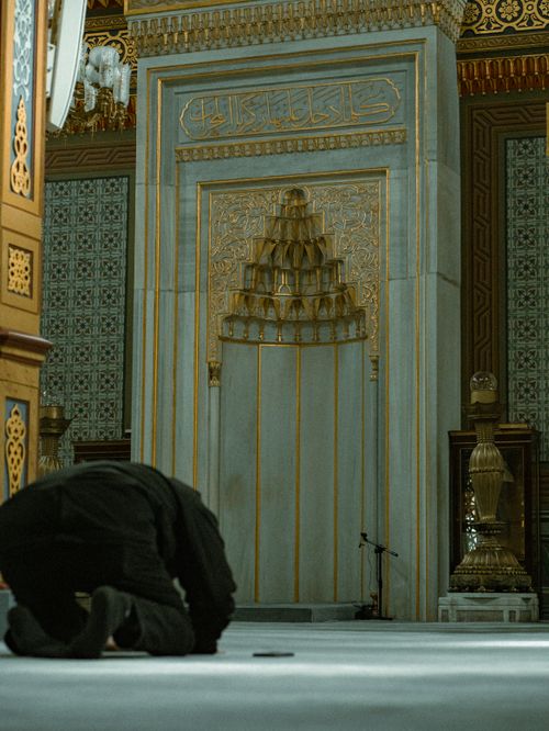 Free A worshipper in prayer inside a richly decorated mosque, showcasing Islamic artistry and tranquility. Stock Photo
