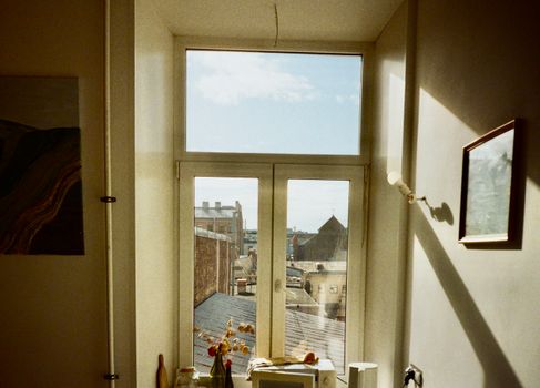 Warm indoor scene capturing a window view of Saint Petersburg's architecture and rooftops under a blue sky.