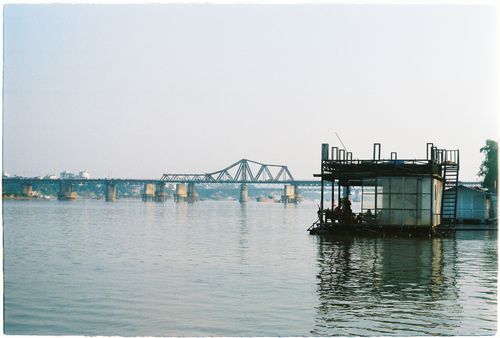 Free Floating house on the river with Long Bien Bridge in the background during daytime. Stock Photo