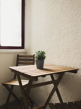 A serene indoor setting with a wooden chair and table, accented by a potted plant.