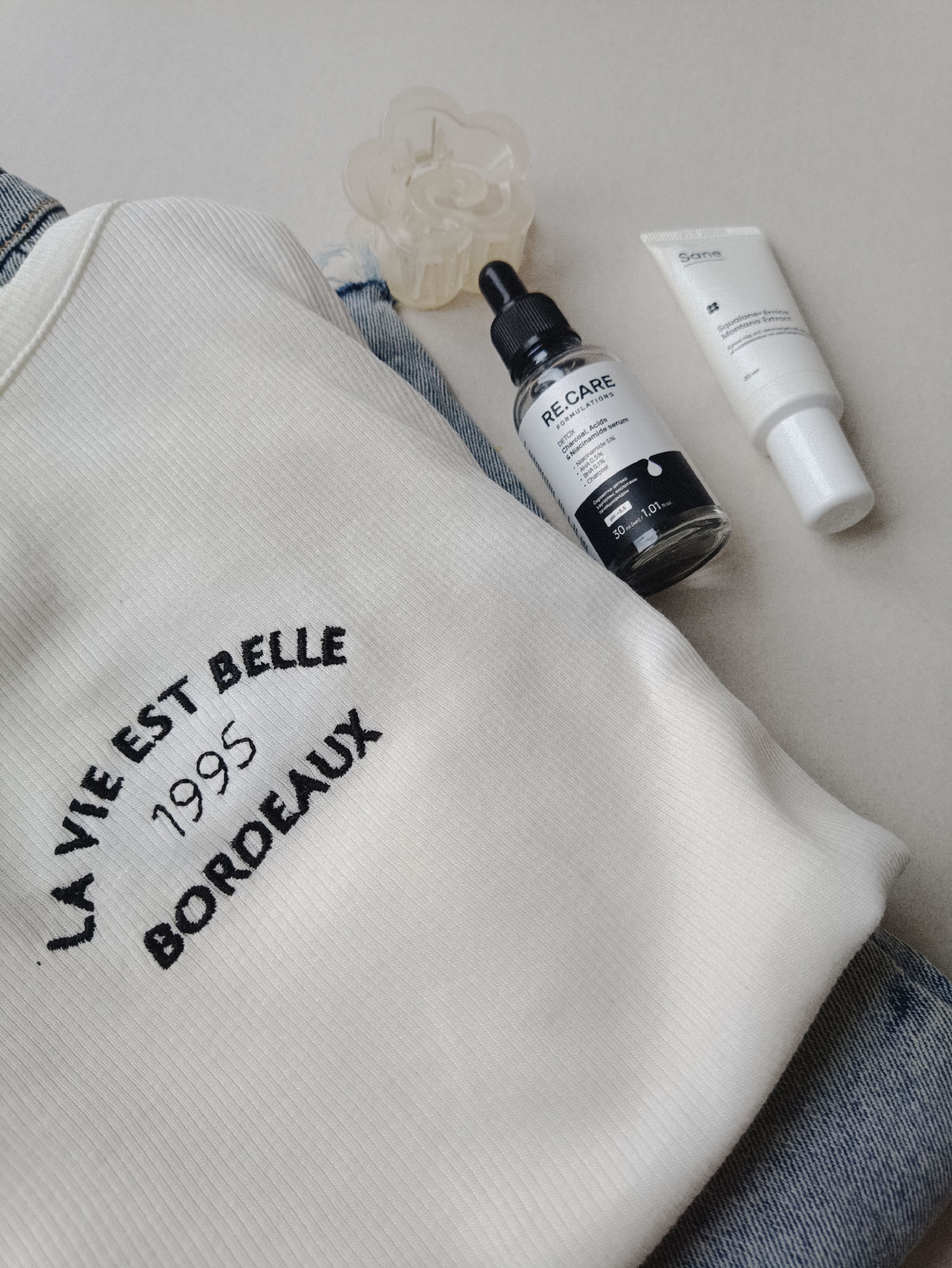 Top view of skincare products with sweater and jeans for a lifestyle flat lay.