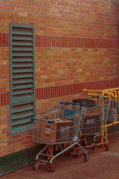 Shopping carts rest against a red brick wall in an urban alley, showcasing city life and retail environment.