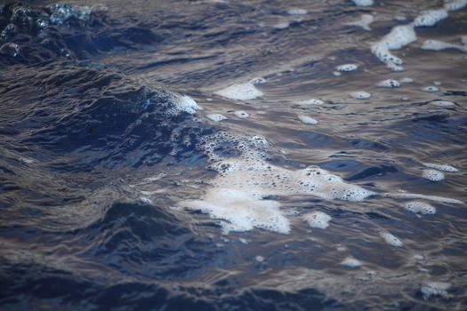 Detailed view of ocean waves with foam, highlighting the natural textures of the sea surface.