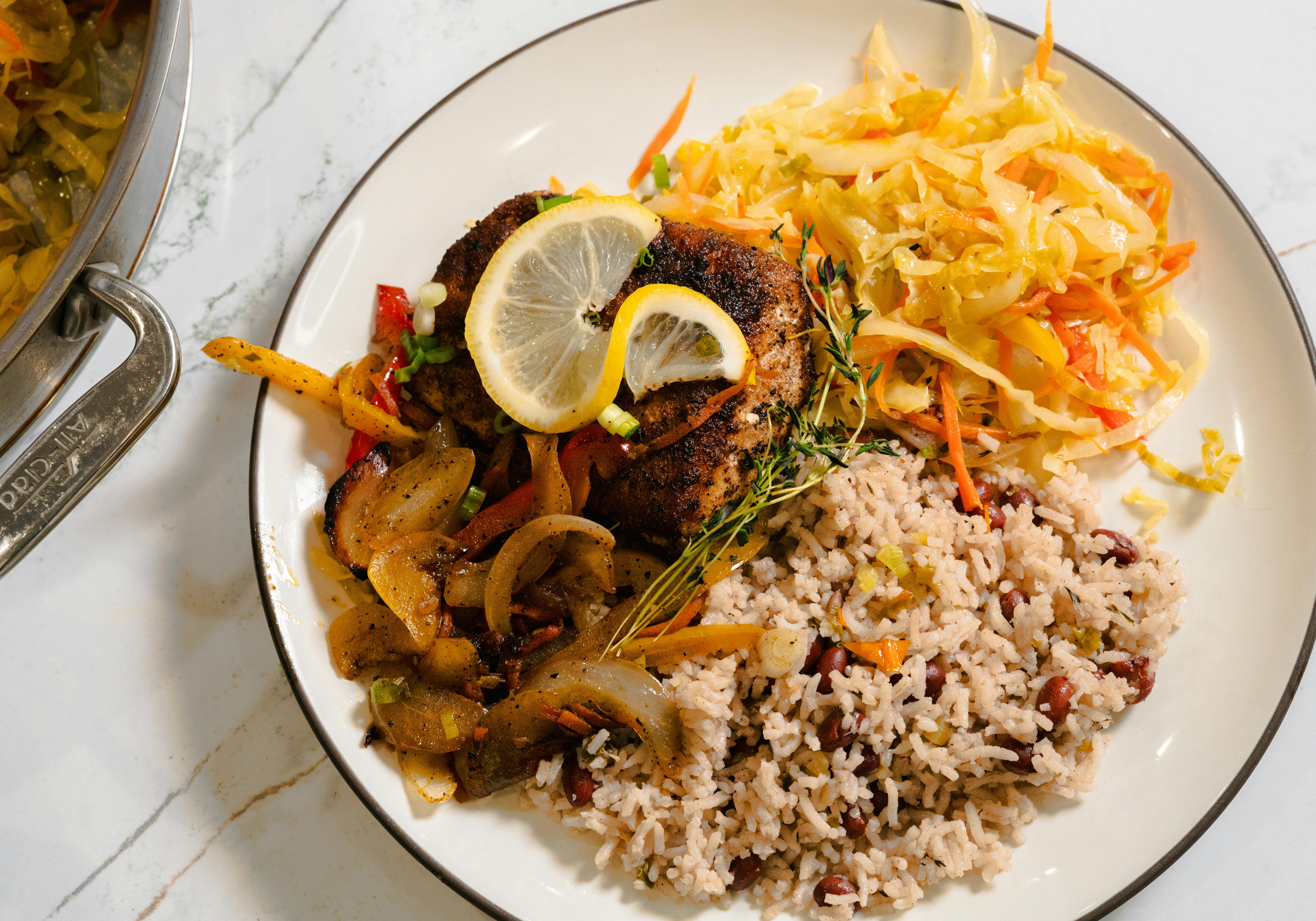 Golden fried snapper topped with colorful pickled onions, carrots, and peppers, drizzled with spiced oil on a white plate