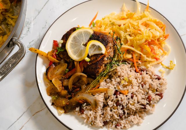 Tantalizing Jamaican escovitch fish served with rice and peas, and colorful cabbage slaw on a plate.