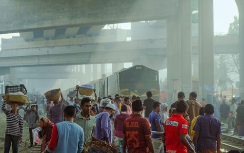 Free Crowded street market under overpasses with people and a passing train. Stock Photo