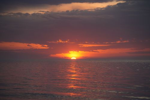 Free Breathtaking sunset over the ocean with vivid orange and purple hues reflecting on the water. Stock Photo