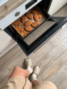 Ginger cookies with leaf shapes freshly baked in a modern kitchen on a wood floor.