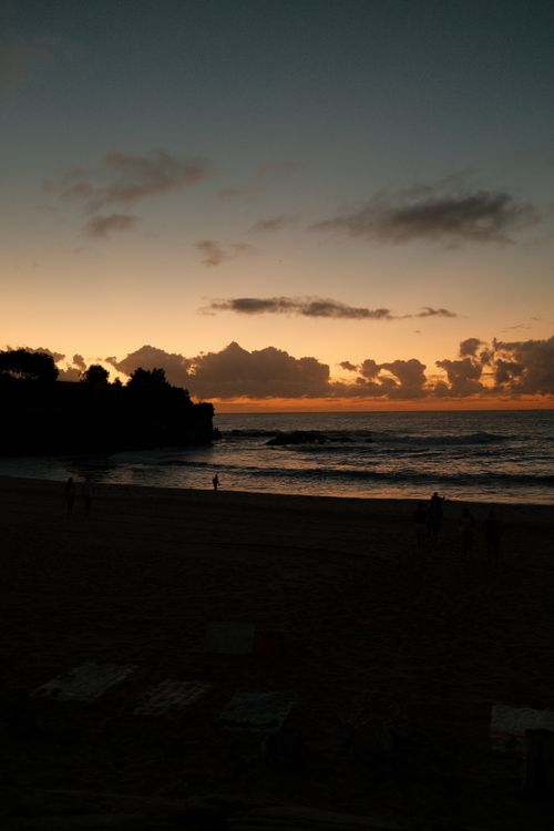 Free Serene sunset view over Sydney beach with silhouettes and calm ocean. Stock Photo