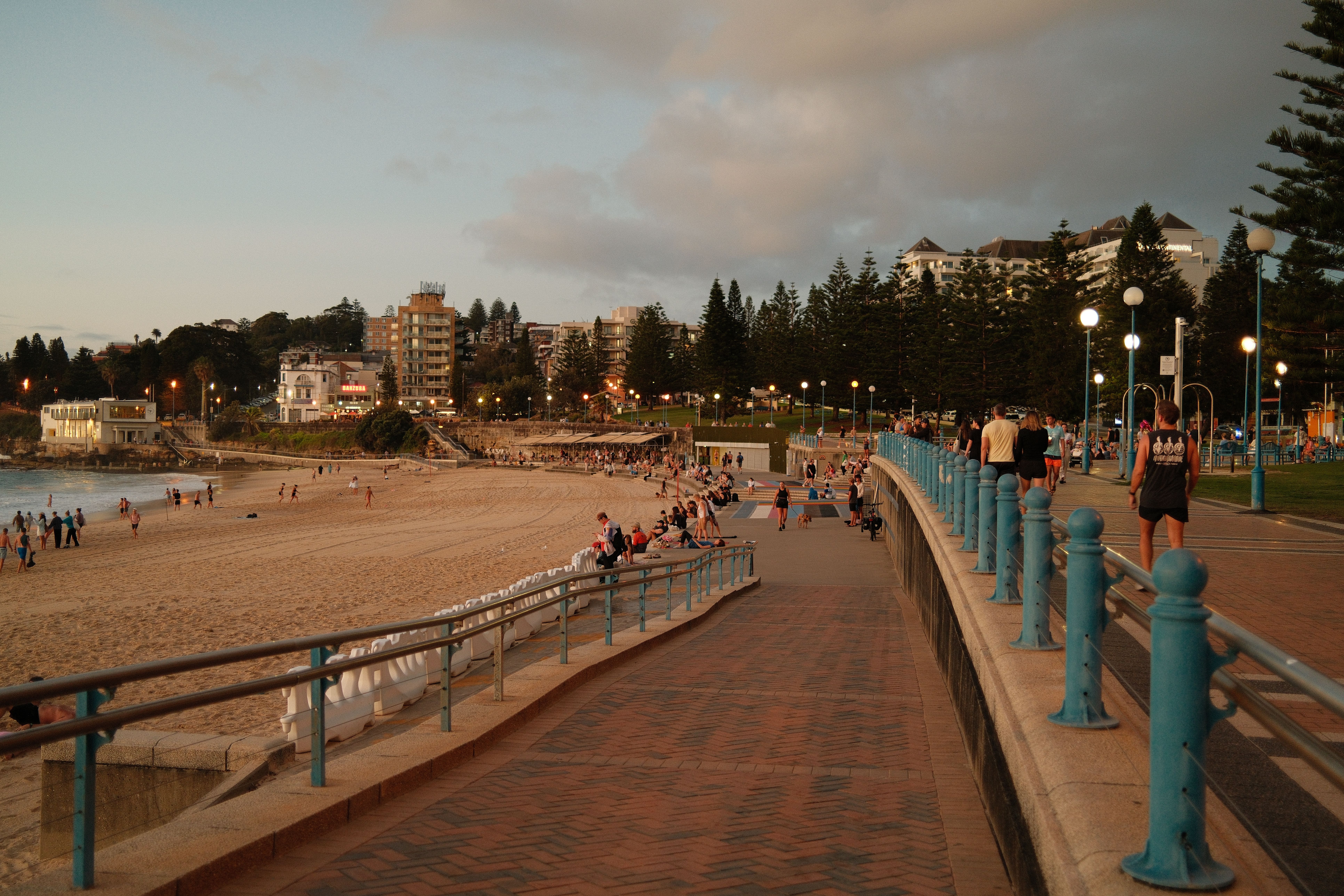People enjoy a sunset stroll along Coogee Beach promenade in Sydney, Australia.