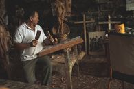 Elderly man skillfully carving wood in an art studio in San Antonio, Ecuador.