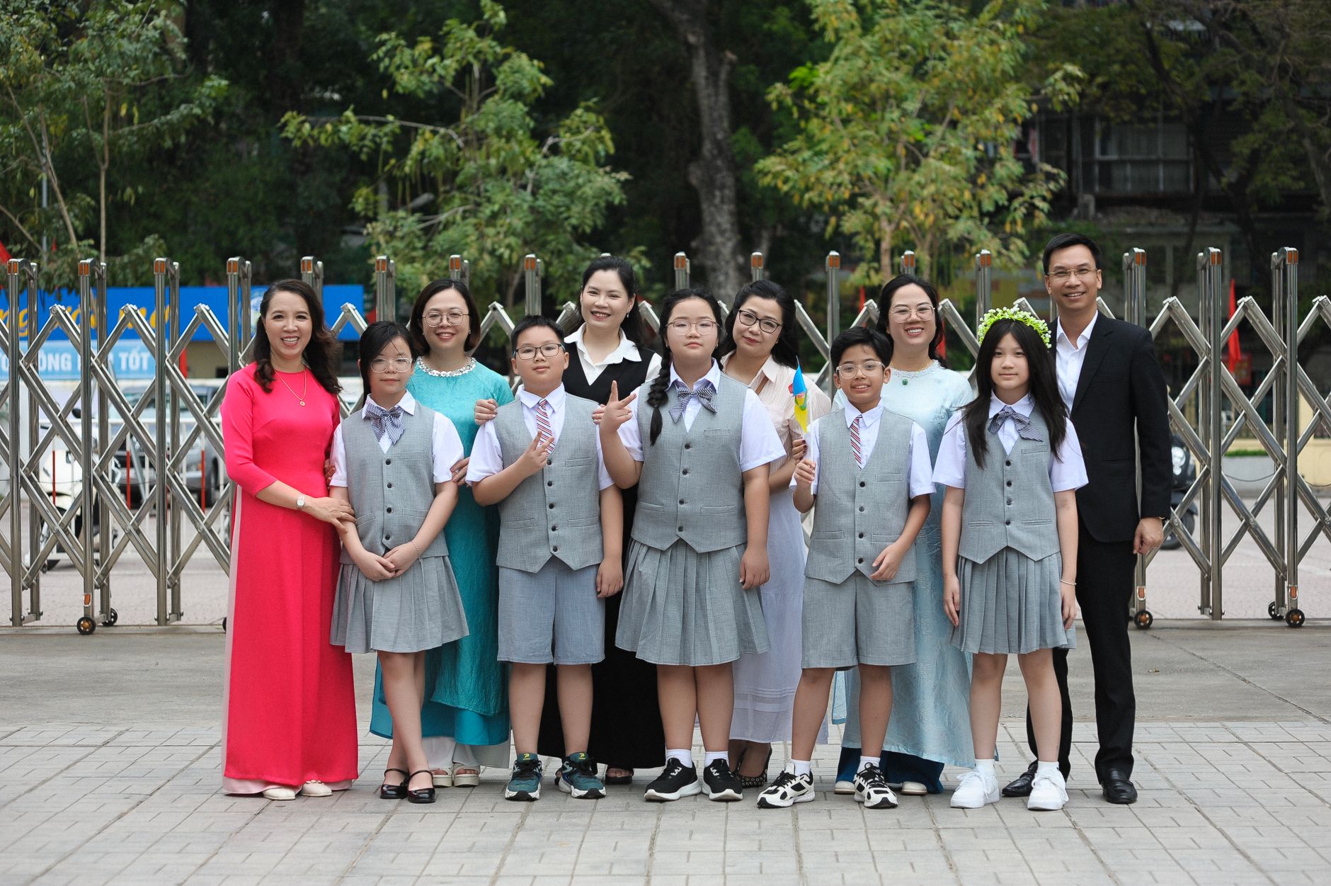 A cheerful group of students and teachers posing together outdoors in school uniforms.