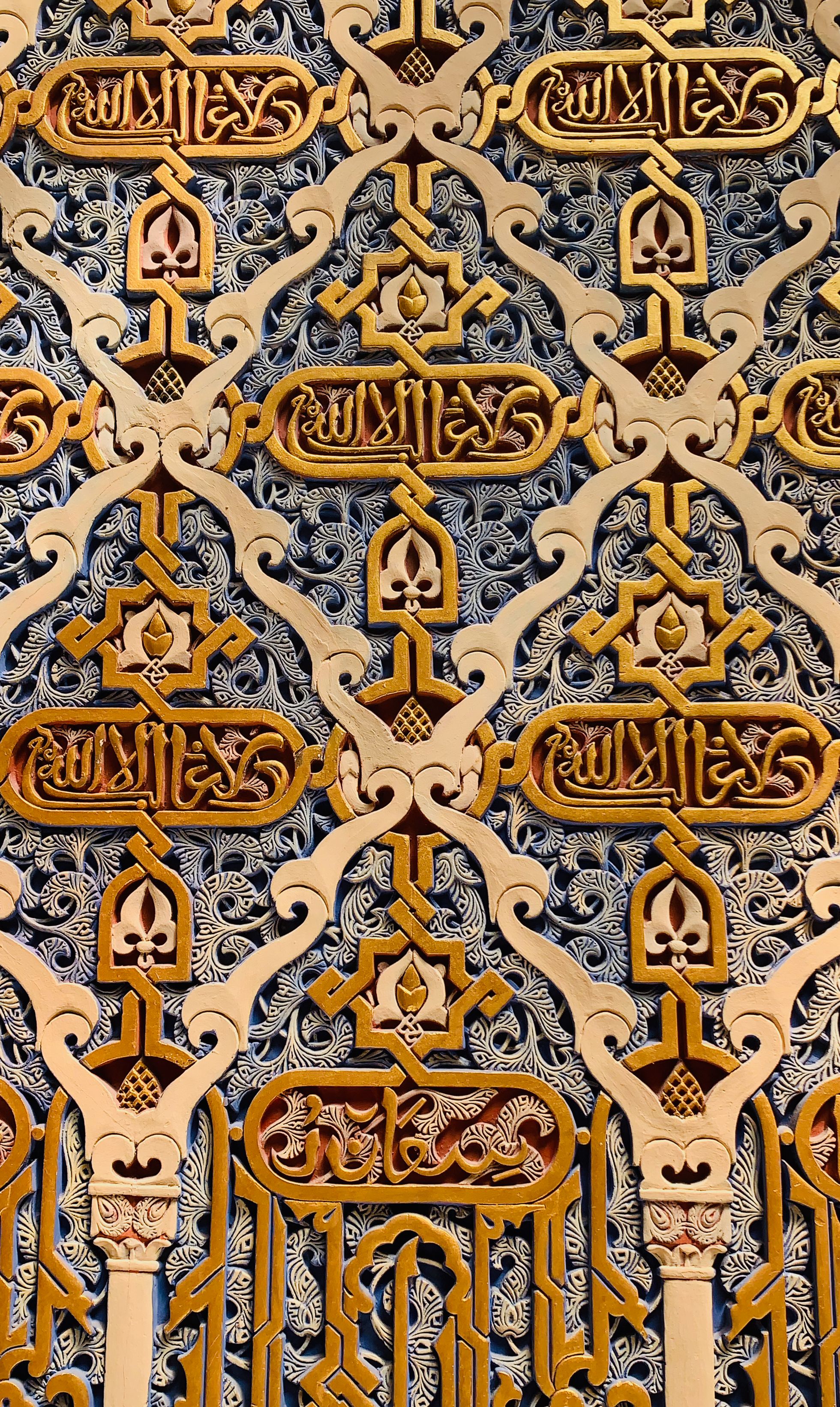 Fotomural Diseño intrincado de pared ornamental islámica con caligrafía dorada, que muestra la rica herencia mora de España.