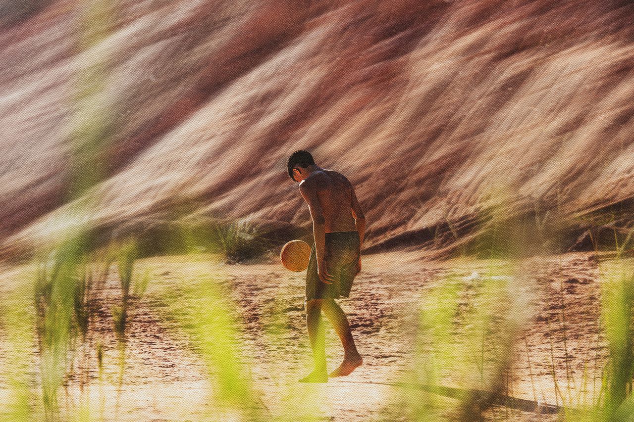 a young man plays soccer on a sandy beach at sunset enjoying the warm