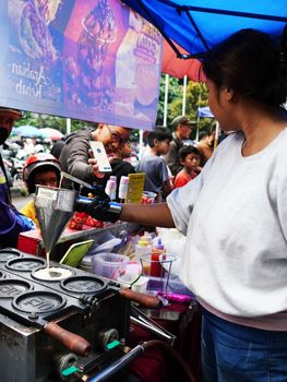 Street food scene in Jawa Barat, Indonesia, showcasing a vendor preparing snacks at a bustling market.