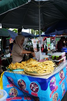 A street vendor prepares and sells traditional fried snacks at a bustling market in Jawa Barat, Indonesia.
