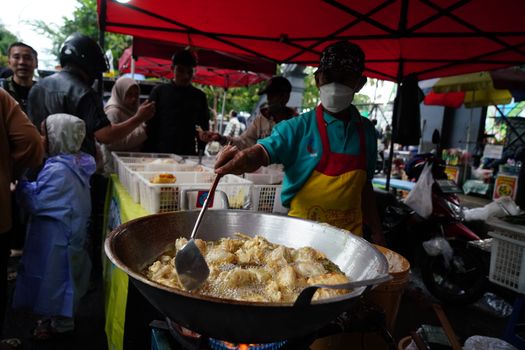 A street vendor fries tofu at a bustling market in Jawa Barat, Indonesia.