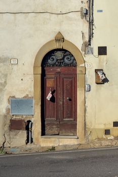 A weathered wooden door with vintage details in Tuscany's charming architecture.