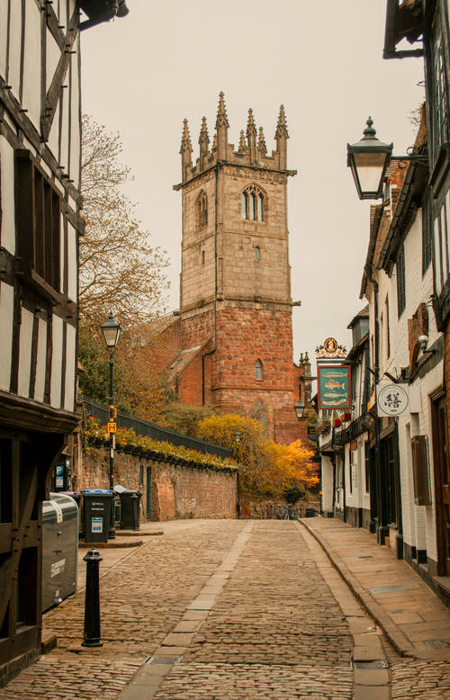 Free Discover a quaint cobbled street leading to a historic church tower in Shrewsbury, England. Stock Photo
