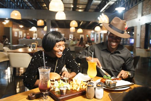 Joyful couple enjoying dinner and drinks at a cozy upscale restaurant, creating a warm ambiance.