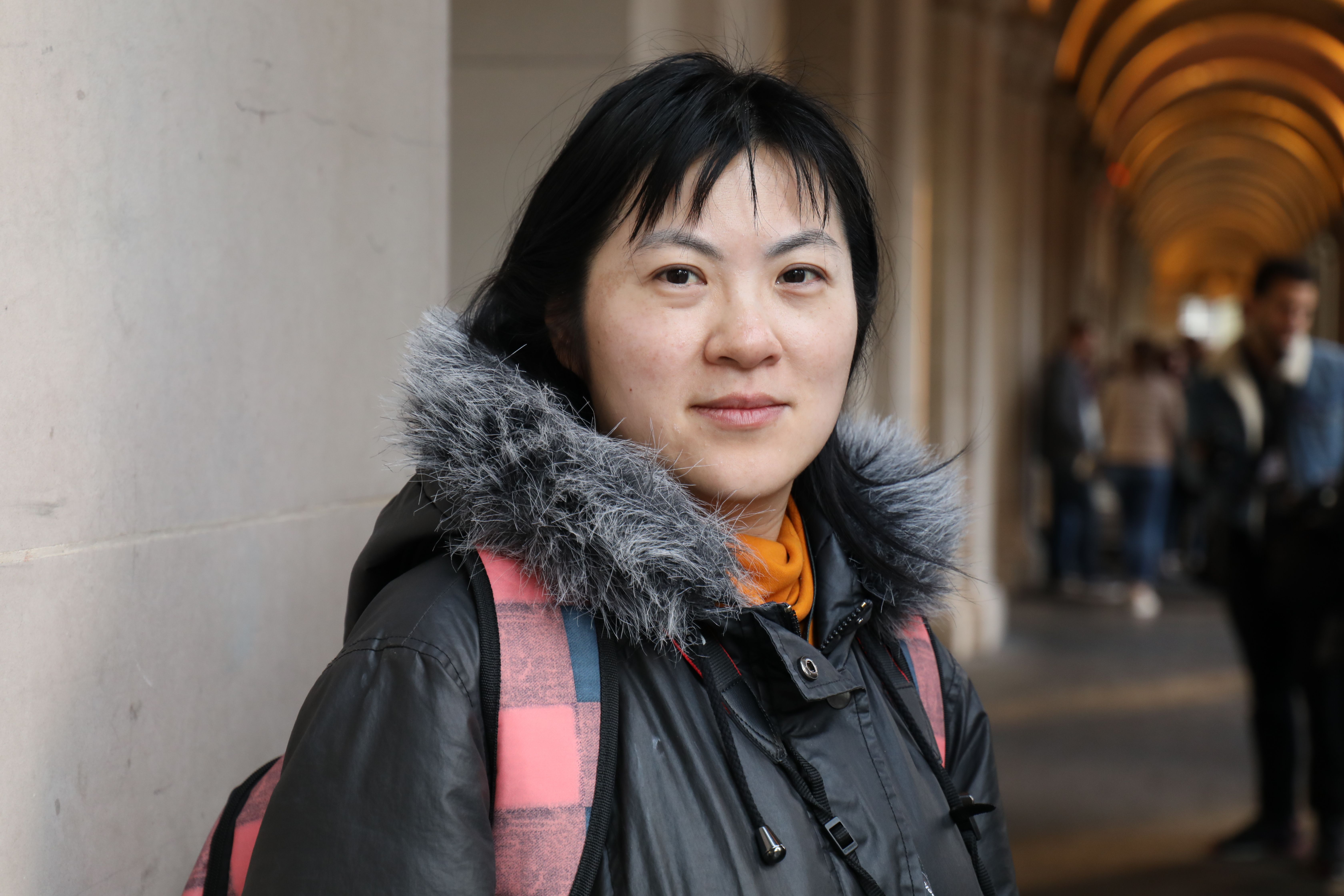 Woman in a fur-trimmed coat posing at an elegant archway in Victoria.