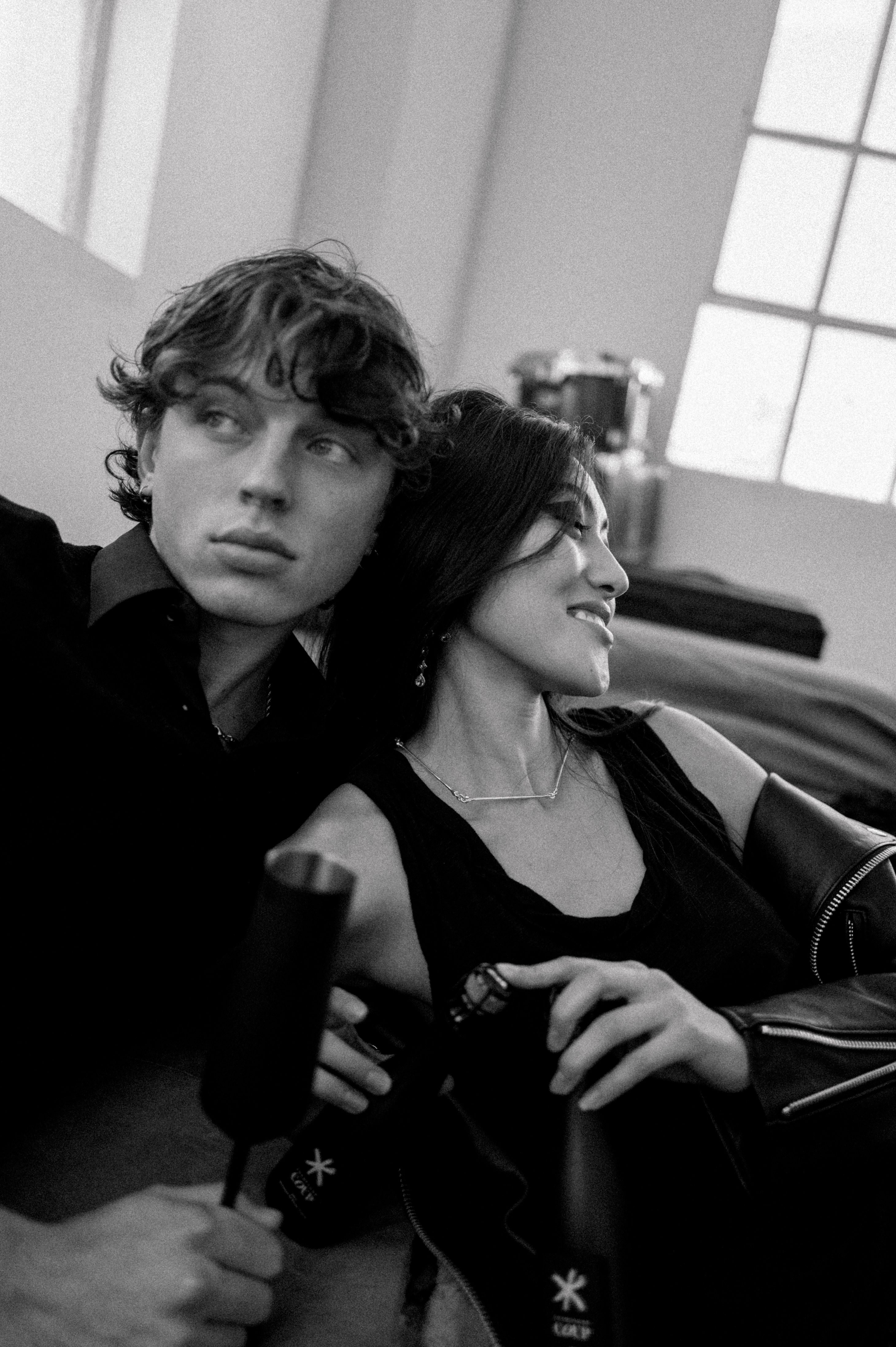Artistic black and white image of a couple relaxing indoors, holding glasses.
