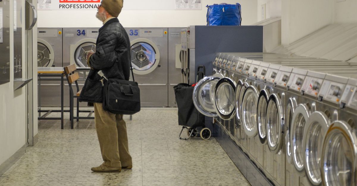 A man stands inside a Berlin laundromat, surrounded by Miele washing machines.