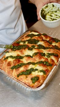 Delicious focaccia bread topped with fresh pesto sauce, ready to enjoy.