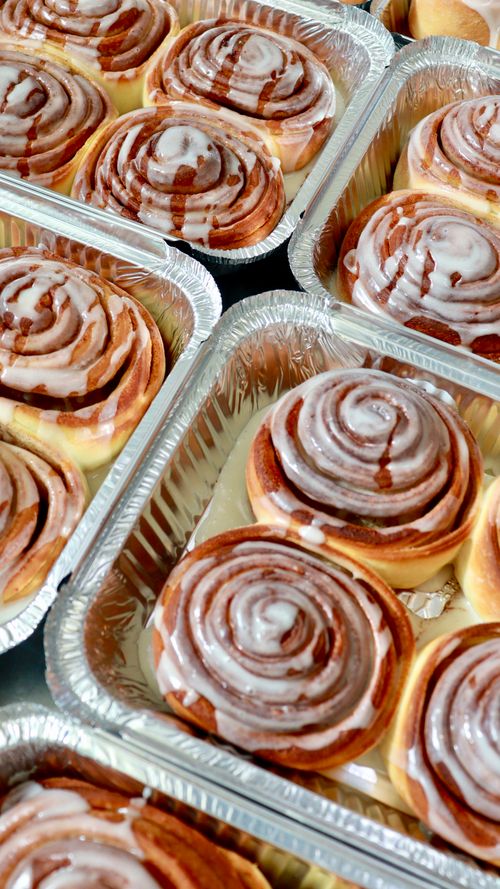 Free Delicious glazed cinnamon rolls in aluminum trays, ready to enjoy. Stock Photo