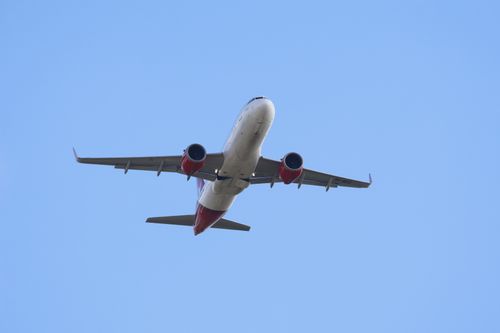 Free A commercial airplane soaring through a bright clear blue sky, captured from below. Stock Photo