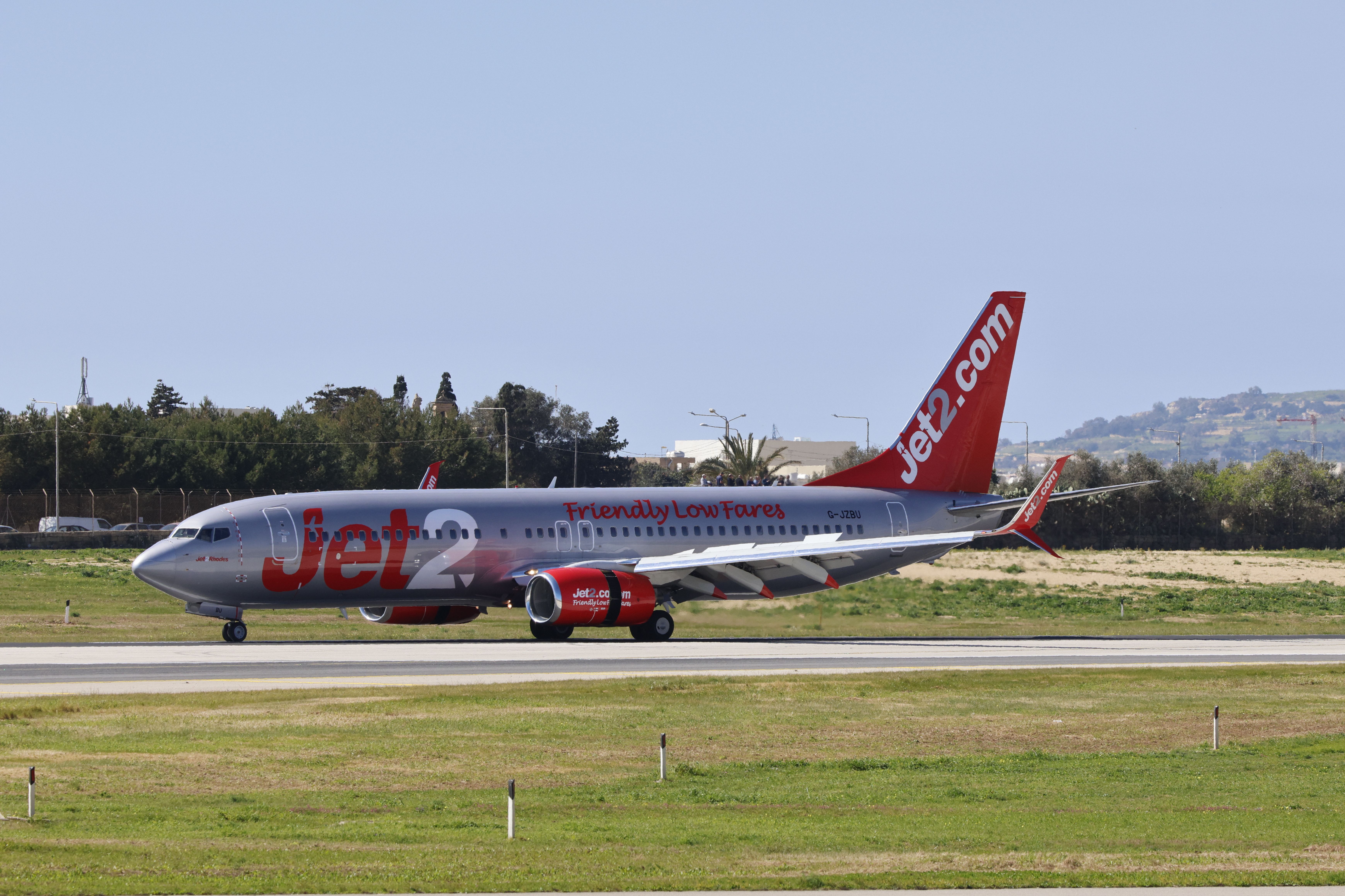 Jet2 airplane on runway with clear sky backdrop, ready for takeoff.