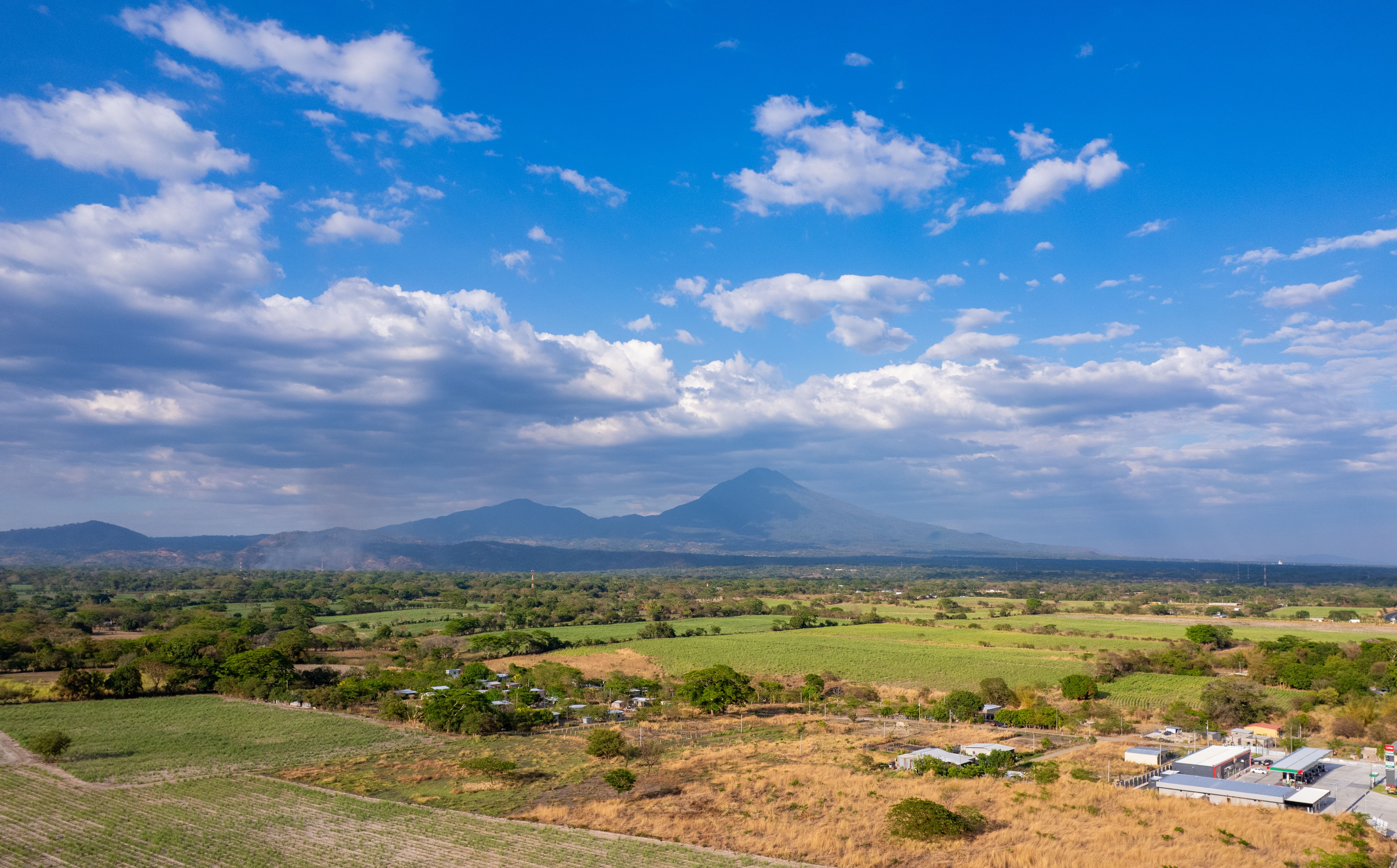 Vista aérea del campo salvadoreño con volcán al fondo