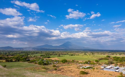 Free Breathtaking aerial view showcasing the lush landscape of El Salvador with a distant volcano under a bright blue sky. Stock Photo