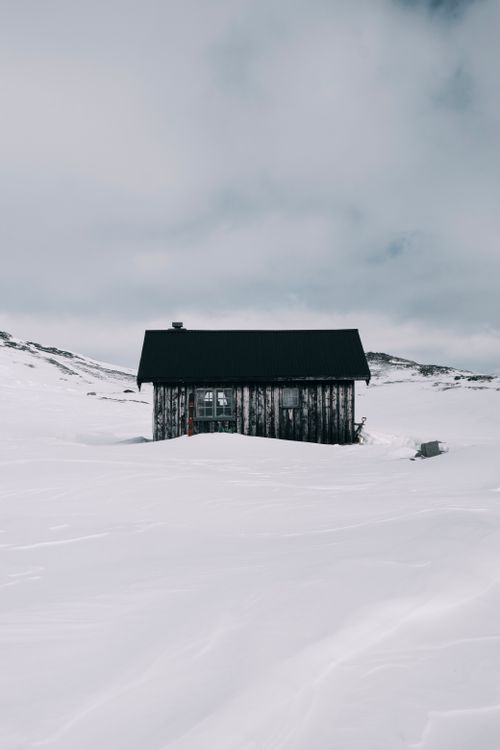 Free A rustic cabin sits isolated in a vast snow-covered landscape, offering a serene winter retreat. Stock Photo
