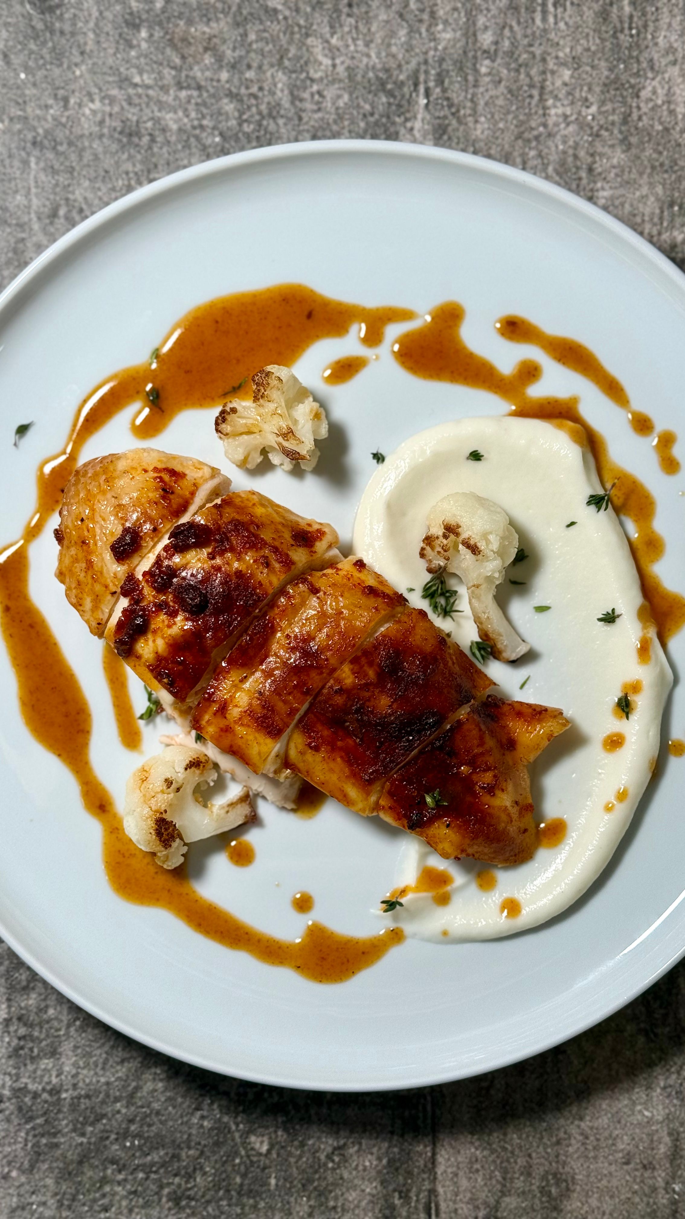 Deliciously plated roast chicken breast with savory sauce and cauliflower puree.
