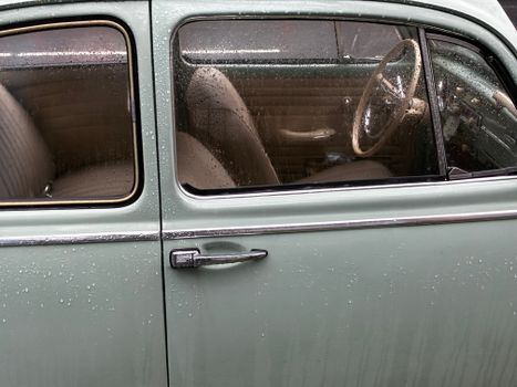 Close-up of a vintage car window with raindrops in Istanbul, showcasing a classic design.