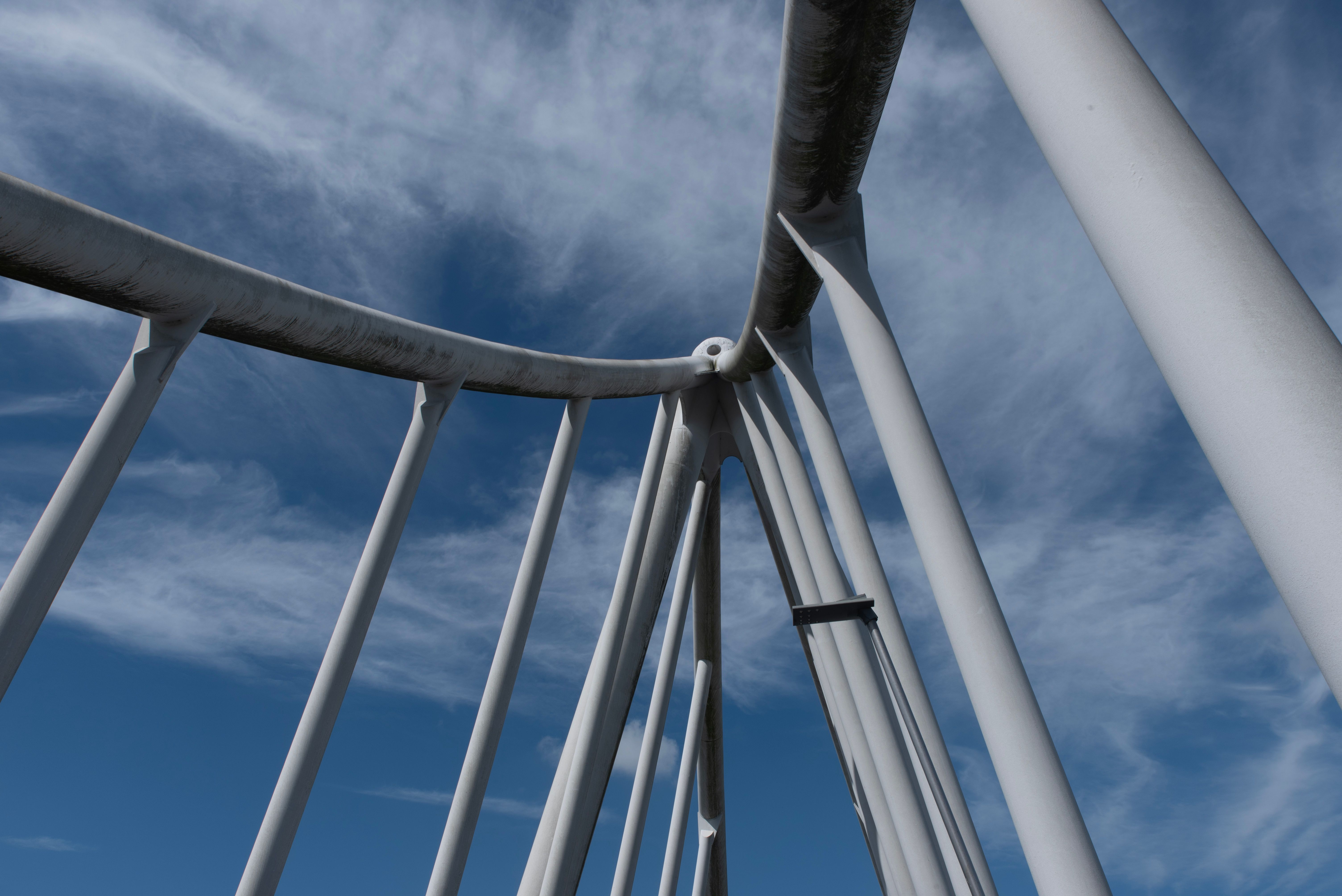 Dynamic view of a modern architectural structure with beams against a vibrant blue sky.