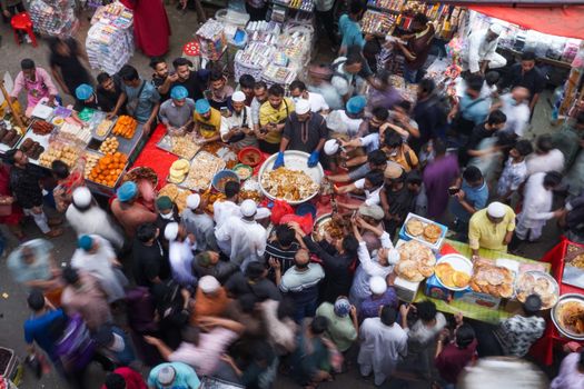 A vibrant scene of people gathering at Chawkbazar Iftar Market in Dhaka, Bangladesh, for traditional foods.