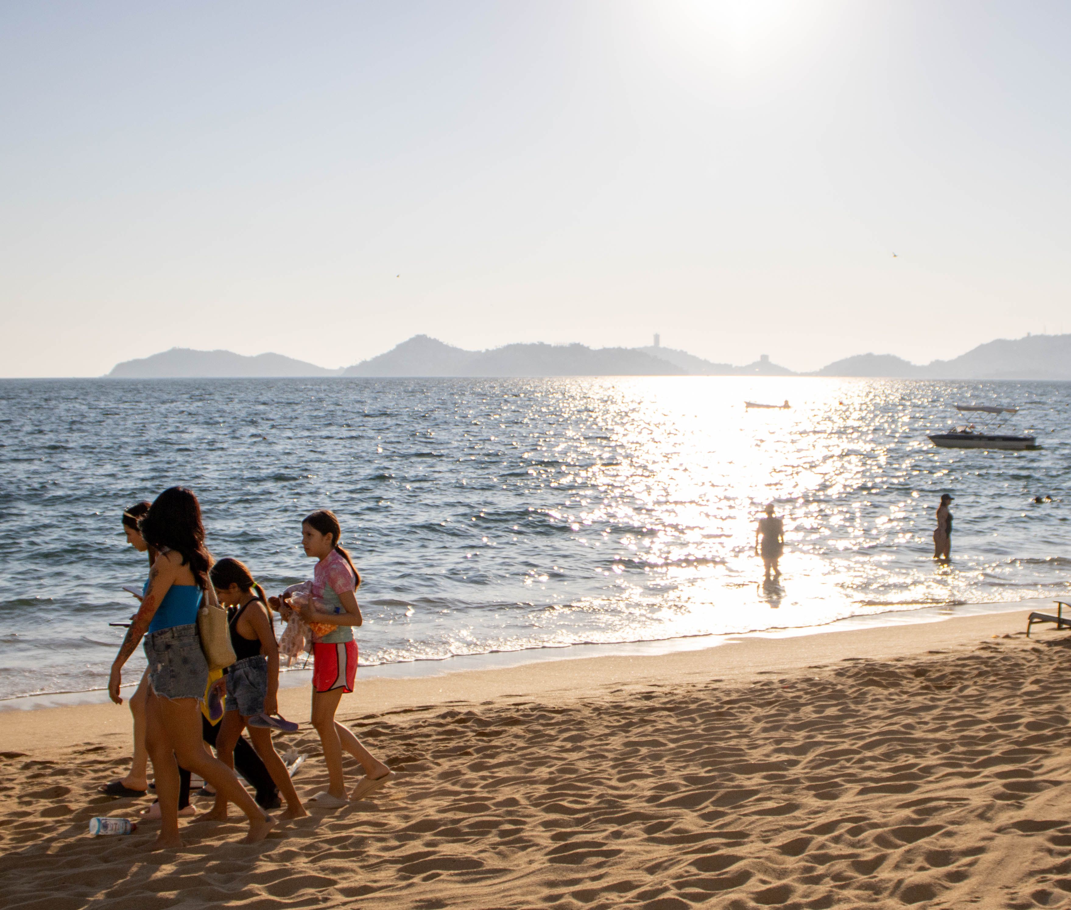 Familia disfrutando de sus vacaciones en la playa en Latinoamérica, usando sus teléfonos para compartir fotos