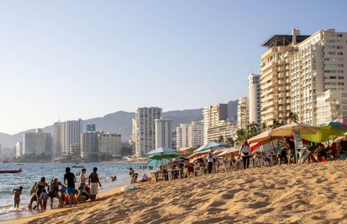 Free Sunny Acapulco beach scene with people and skyscrapers in the background. Stock Photo