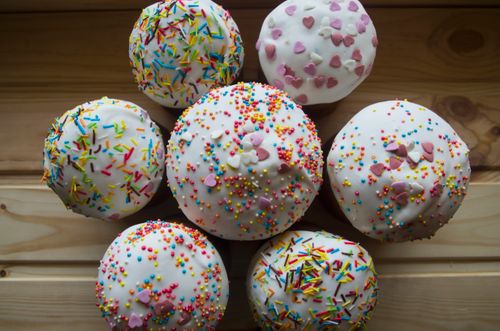 Free Top view of assorted cupcakes with colorful sprinkles and heart shapes on wooden surface. Stock Photo