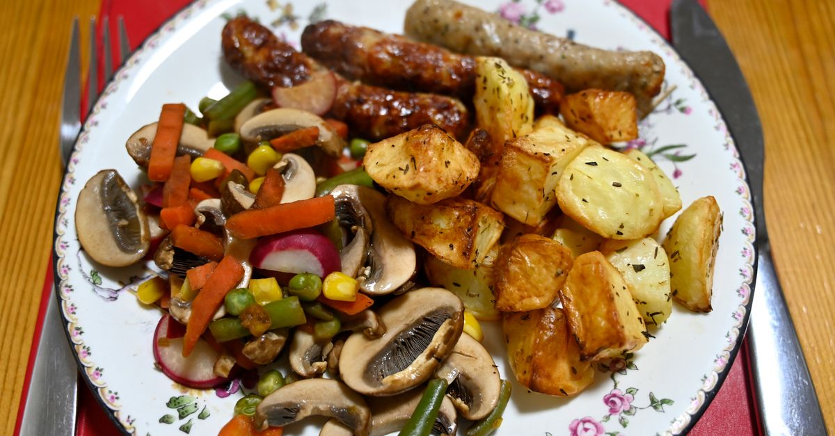 Colorful plate with roasted vegetables, beans, and grains on a wooden board