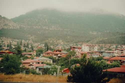 Free Charming village nestled in misty mountains with colorful roofs and lush greenery. Stock Photo