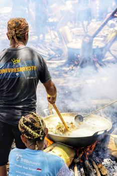 Capturing a traditional outdoor cooking scene in Central Java, Indonesia. Vibrant atmosphere with locals involved.