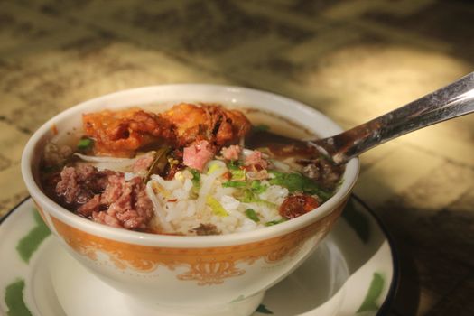 A savory bowl of Indonesian Sop Buntut soup with rice, garnished with fresh herbs.