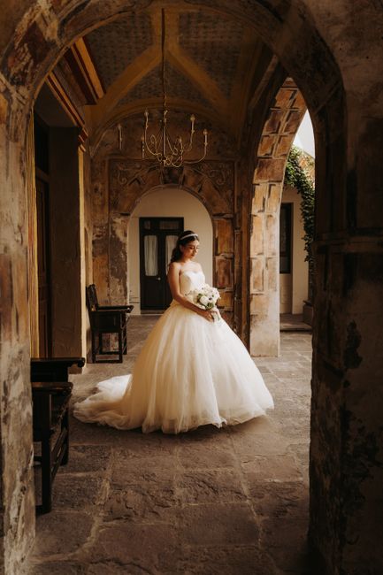 Bride in white dress standing in a historic courtyard in Puebla, Mexico.